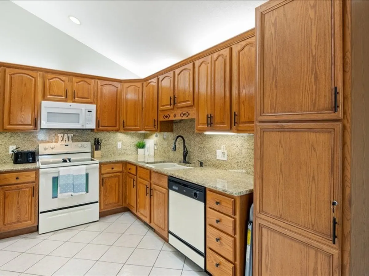 A welcoming kitchen with wooden cabinetry, granite countertops, stainless steel appliances, and a well-organized sink area. The space looks thoughtfully prepared for cooking and group meal preparation, suggesting ample room for multiple cooks and easy access to essentials.