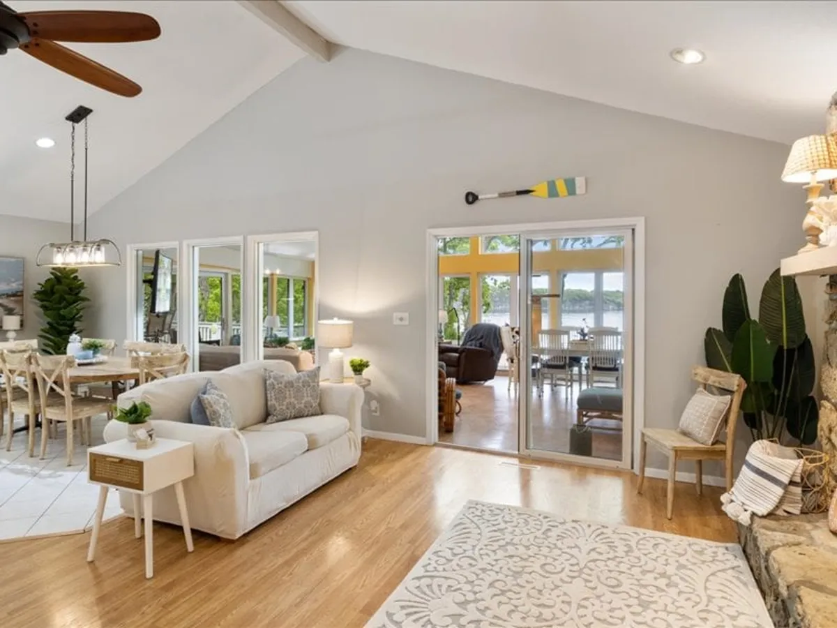 A cozy space combining a comfortable sofa and an adjacent dining area, with large glass doors leading to an outdoor space. Decorative elements, such as the oar on the wall, add a lakeside charm, and the overall mood is warm and lively, ideal for shared meals and conversation.