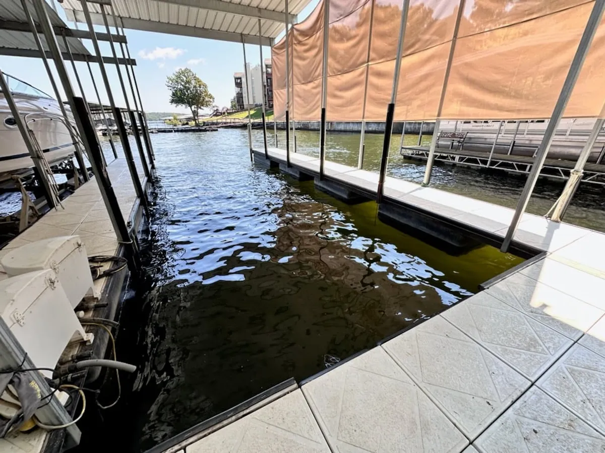A calm dock area with a boathouse and smooth water surface, this image invites viewers to imagine boating, fishing, and relaxing by the water. The tranquil mood and practical setup echo the convenience and enjoyment of water access.