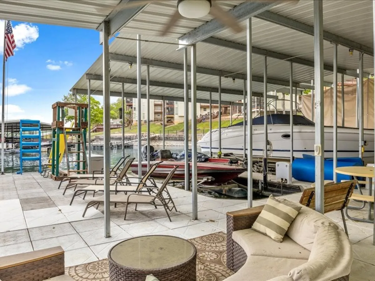 This exterior image features boats docked in the marina, lounge chairs for relaxing, and an outdoor seating area right at the water's edge. The setting is casual and leisure-oriented, with clear cues of water-based activities and social gatherings by the dock.
