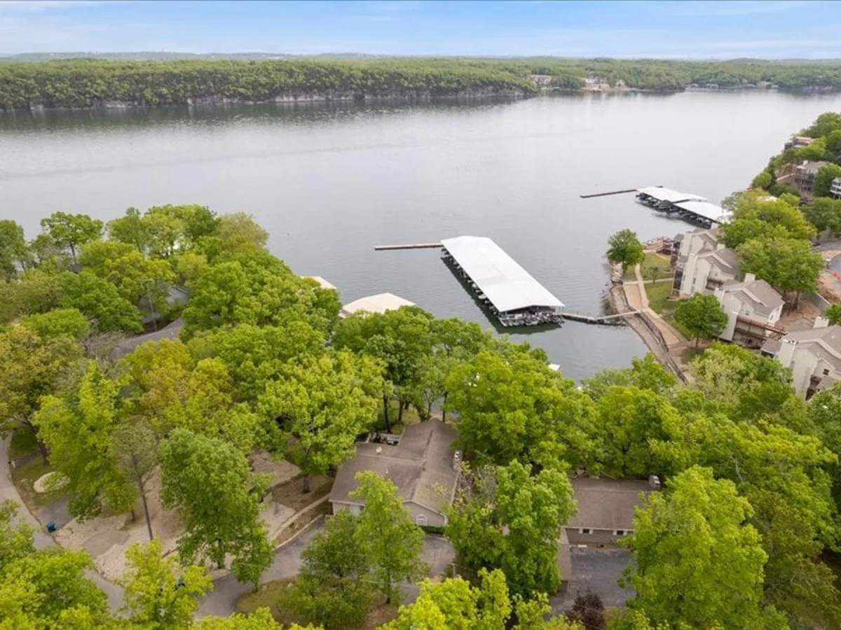 Expansive lake views framed by a boathouse, lush greenery, and nearby homes. The setting is peaceful and relaxed, showing the broader context of the lake environment—ideal for exploring, socializing, and group excursions.