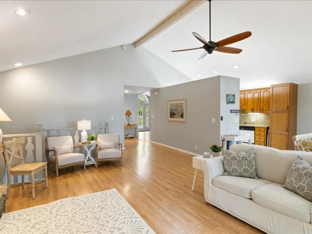 A cozy interior with a sofa adorned with decorative cushions, a wooden dining area, and attractive light fixtures. The scene exudes warmth and comfort, ideal for relaxing or entertaining in shared spaces.